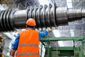 Industrial worker inspecting large metal component with precision tools.