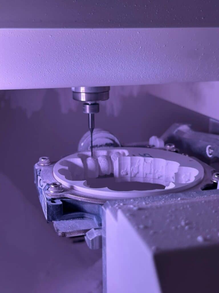 Detailed view of CNC machine milling process with purple lighting, highlighting precision engineering.