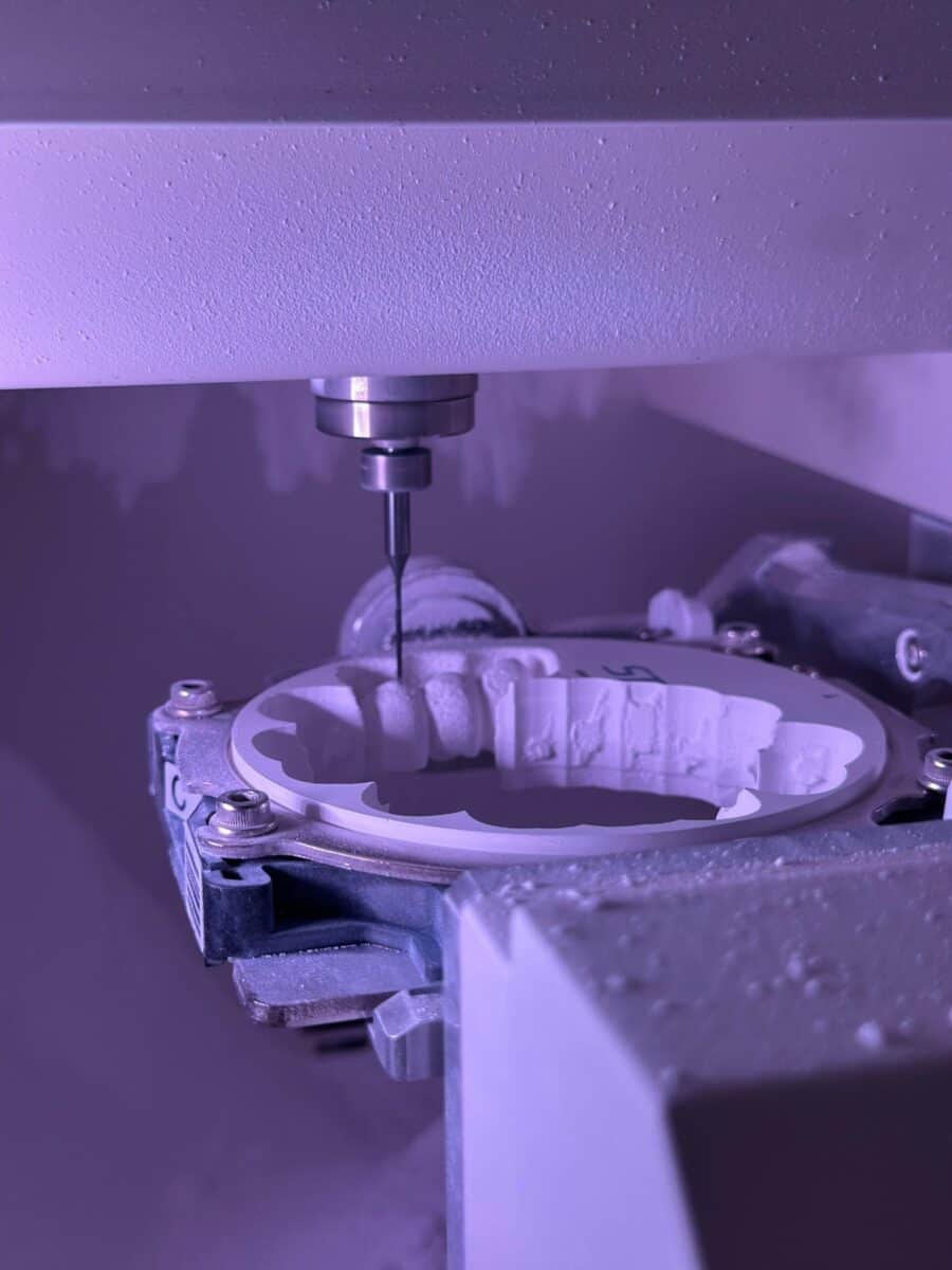 紫色の照明が精密工学を際立たせる、CNCマシンのフライス加工工程の詳細図。