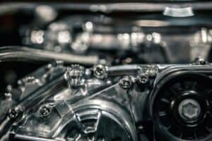 Close-up of high-strength flange bolts securing an industrial machine engine, showcasing precision threading and durable materials used in heavy-duty applications.