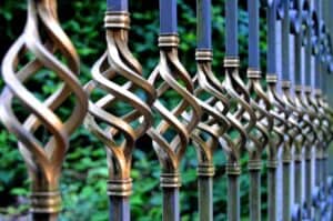 Industrial metal fence with decorative twisted bars and blue caps.