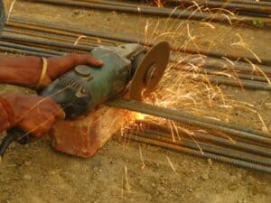 Angle grinder cutting steel reinforcement bars with sparks flying.