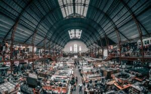 Large industrial warehouse showcasing extensive storage racks and machinery under a high, curved metal roof.