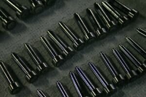 Close-up of high-strength alloy steel screws arranged in rows, showcasing their precision-machined threads and polished surfaces for industrial applications.