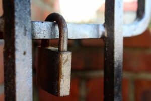 Rusty padlock securing a metal gate, symbolizing industrial security and durability in steel forging applications.