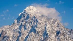 Snow-capped mountain peak under a blue sky, showcasing rugged terrain and alpine scenery.