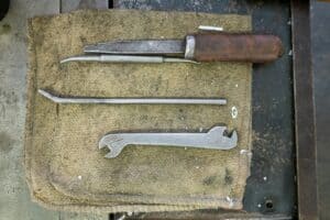 Tools for casting iron parts, including a chisel, a pry bar, and a wrench, displayed on a work surface.
