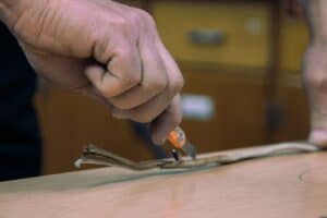 a man is cutting a piece of wood with a pair of scissors