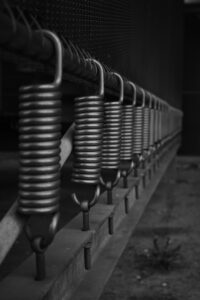 Close-up of spring steel coils and hooks used in industrial machinery, highlighting durable materials suitable for heavy-duty engineering projects.