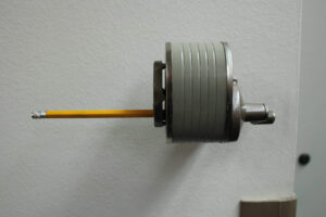 Close-up of a high-strength industrial flange bolt with a yellow safety pin, mounted on a plain wall, used in heavy machinery and construction applications.