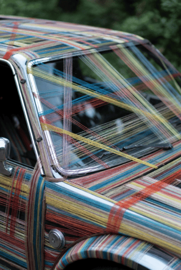 Up of a classic car covered with multicolored threads, highlighting the importance of proper fastener selection and thread types in vehicle manufacturing and repair.