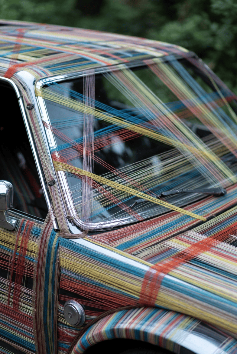 Colorful threads woven across a vintage car's windshield and body, illustrating intricate fastening techniques and thread types used in automotive assembly. Colorful threads woven across a vintage car's windshield and body, illustrating intricate fastening techniques and thread types used in automotive assembly.