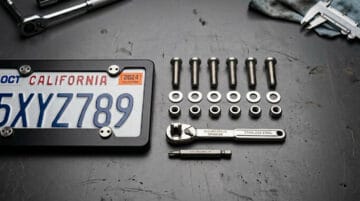 작업대 위의 플랜지 볼트, 나사, 공구의 클로즈업으로 제조 및 건설에 사용되는 내구성 높은 산업용 패스너를 보여줍니다.